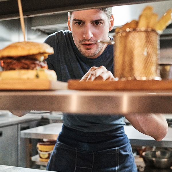 Young male chef looks over meals prepared and waiting for delivery